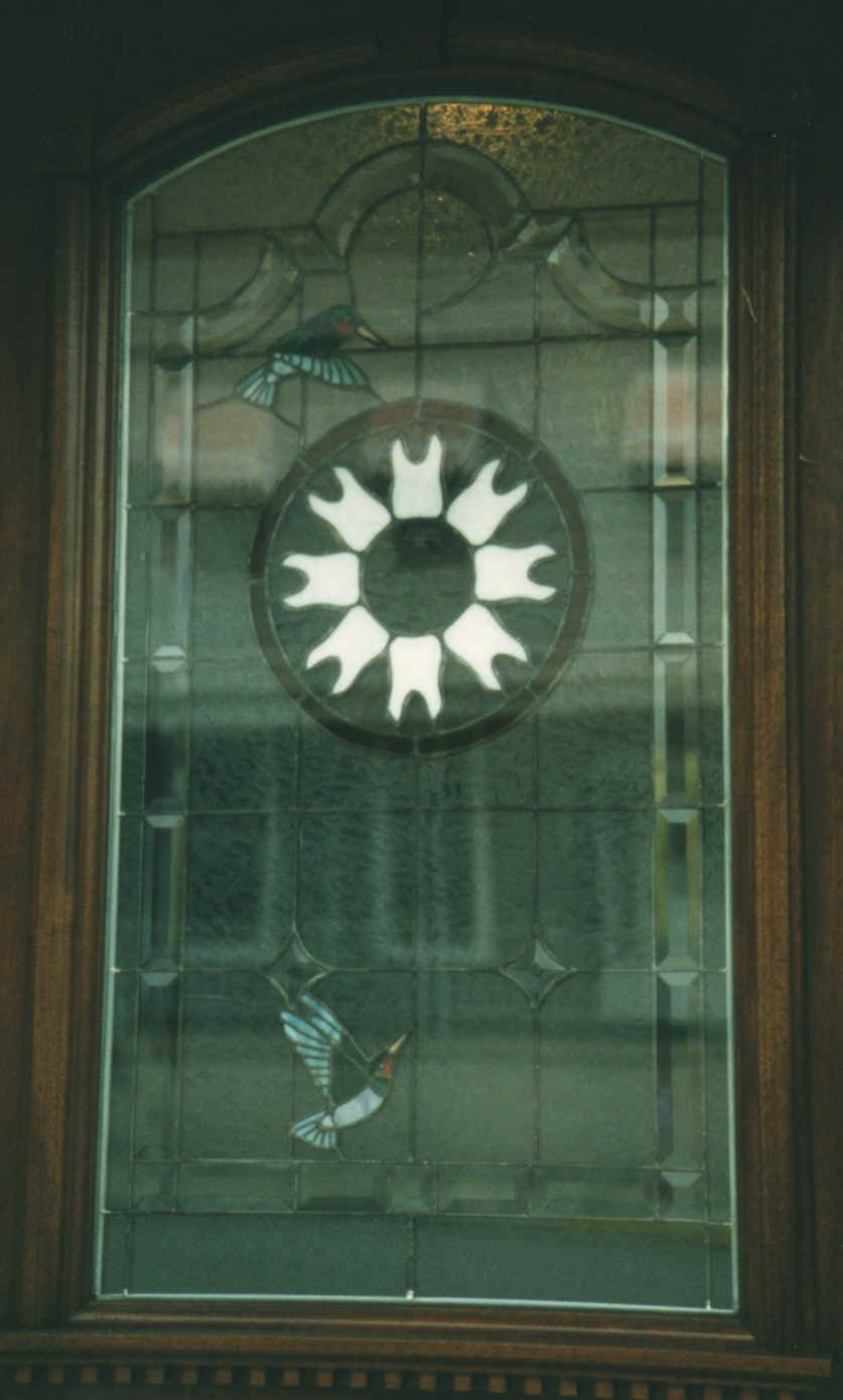 Picture of our front door, with our tooth logo and hummingbirds in a stained glass window